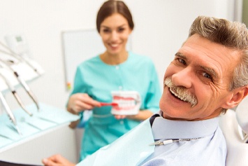 Old man smiling with dentist after receiving All-On-4 in Waco