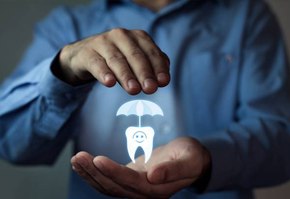 Man’s hands holding animated tooth under umbrella