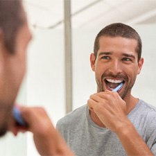 Man smiling while brushing teeth 
  
  