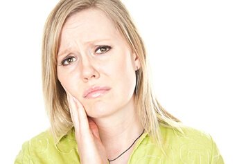 Female with blonde hair painfully touching her cheek