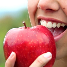 Closeup of patient with dental implants in Waco eating an apple