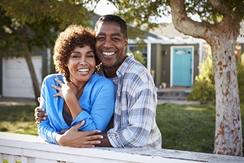 couple on their porch smiling with dental implants in Waco