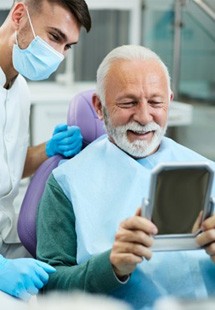 a patient smiling after receiving tooth replacements