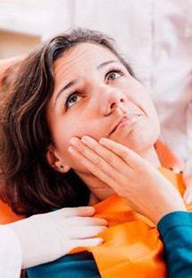 a patient holding cheek due to tooth pain