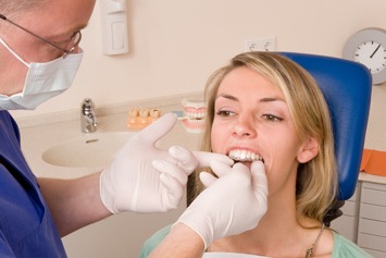 Dentist placing a woman’s Invisalign tray