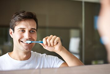 Male in white shirt brushing his teeth