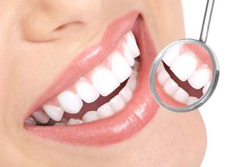 Dental mirror next to woman’s beautiful, bright smile