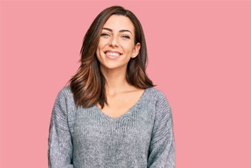 Portrait of smiling woman against pink background