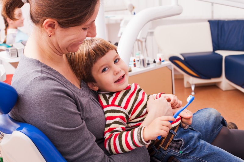 mother sitting holding child dentist chair