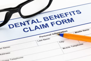 Dental benefits claim form with glasses and ballpoint pen.