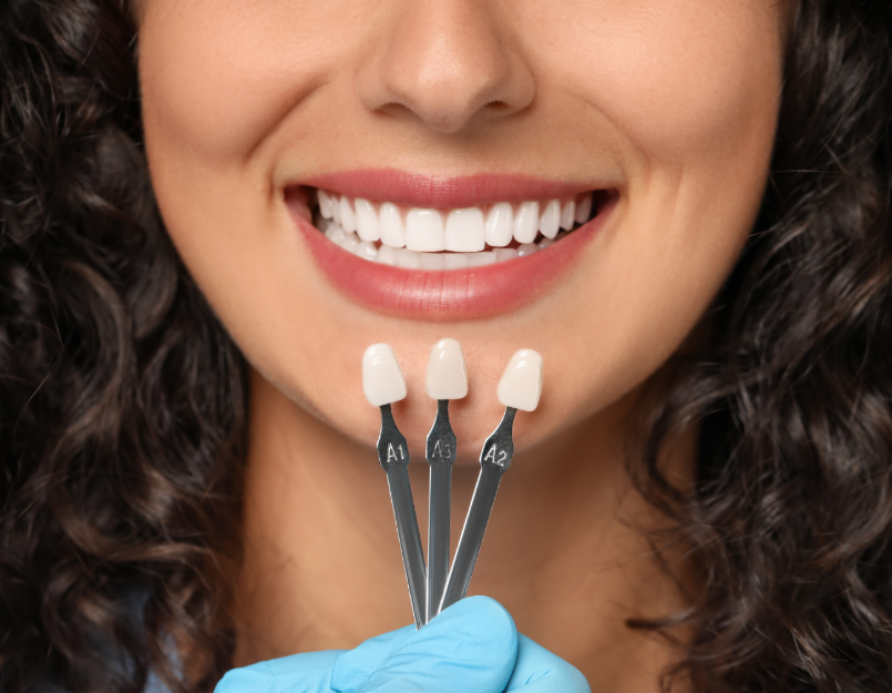 Close up of woman's face with hand holding veneers